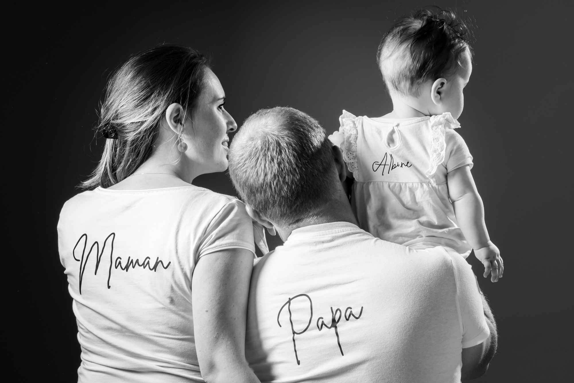 Portrait d'une famille avec un bébé, vue de dos, en noir et blanc.
