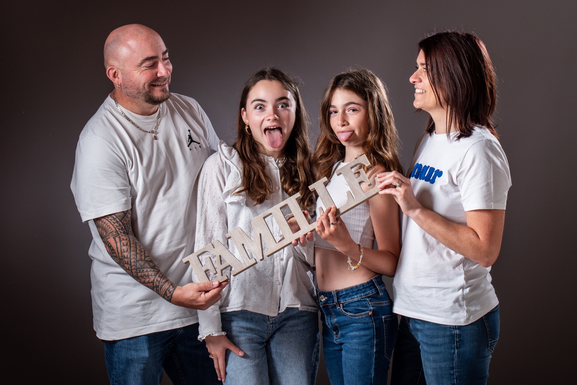 Séance photo familiale joyeuse en studio avec quatre membres de la famille.