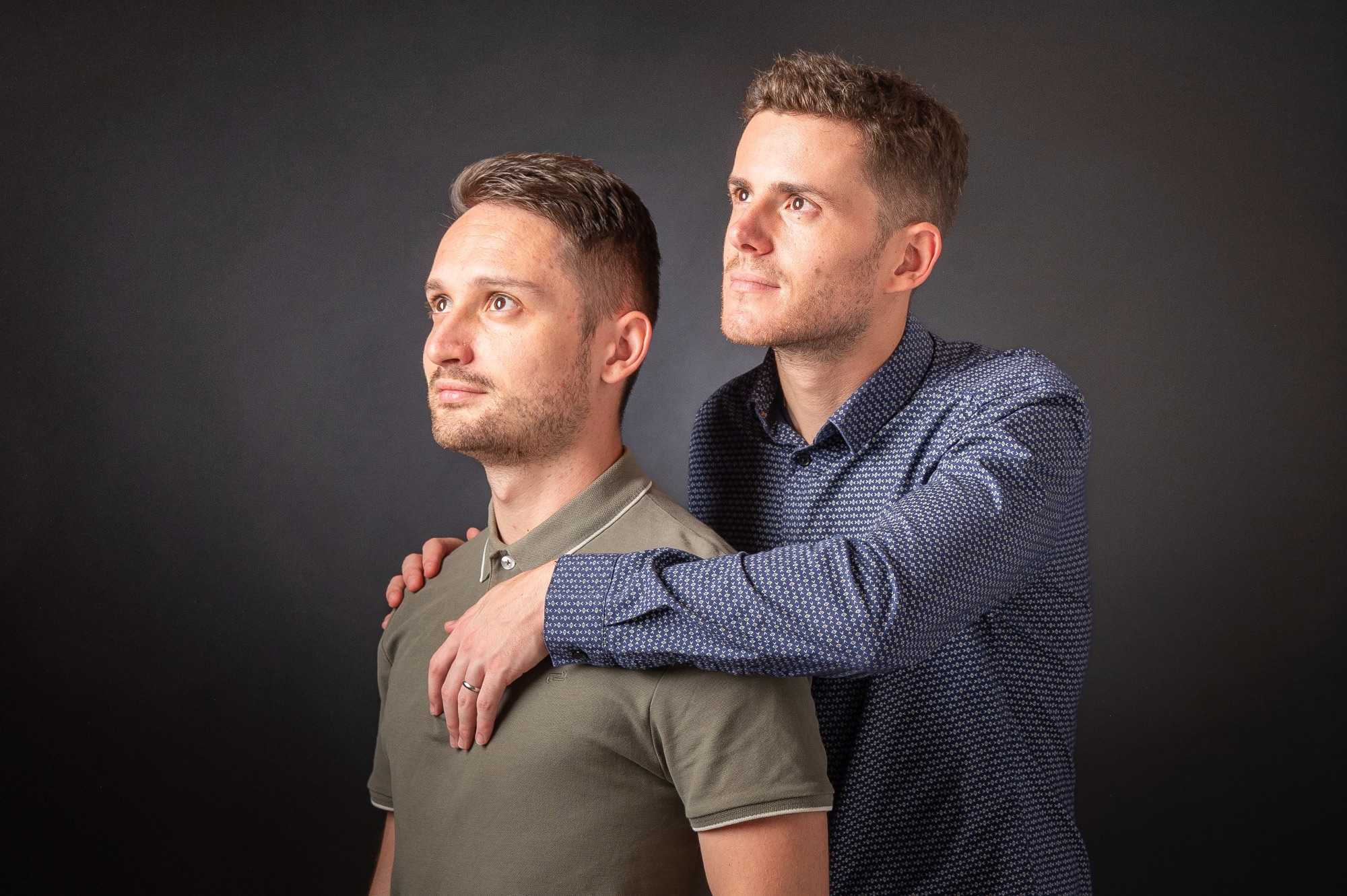 Portrait de deux hommes en studio, regard sérieux et complice.