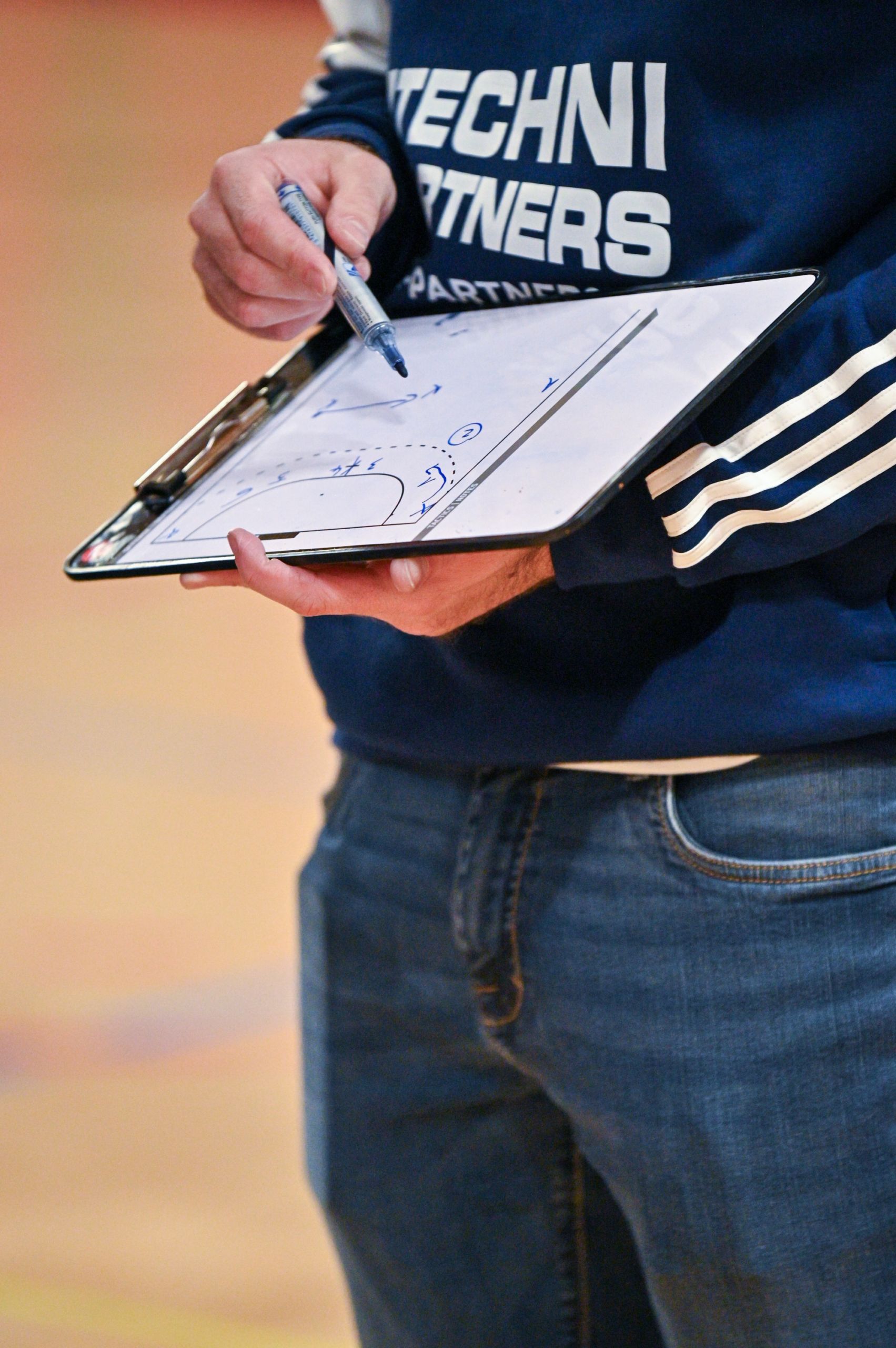 Un entraîneur prenant des notes sur un tableau lors d'un match de sport.