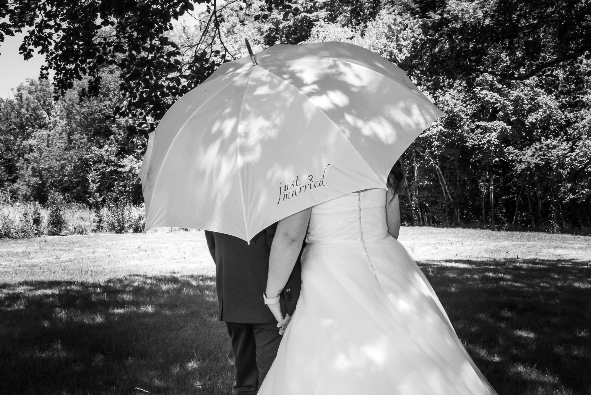 Mariage en extérieur avec couple sous un parapluie blanc.