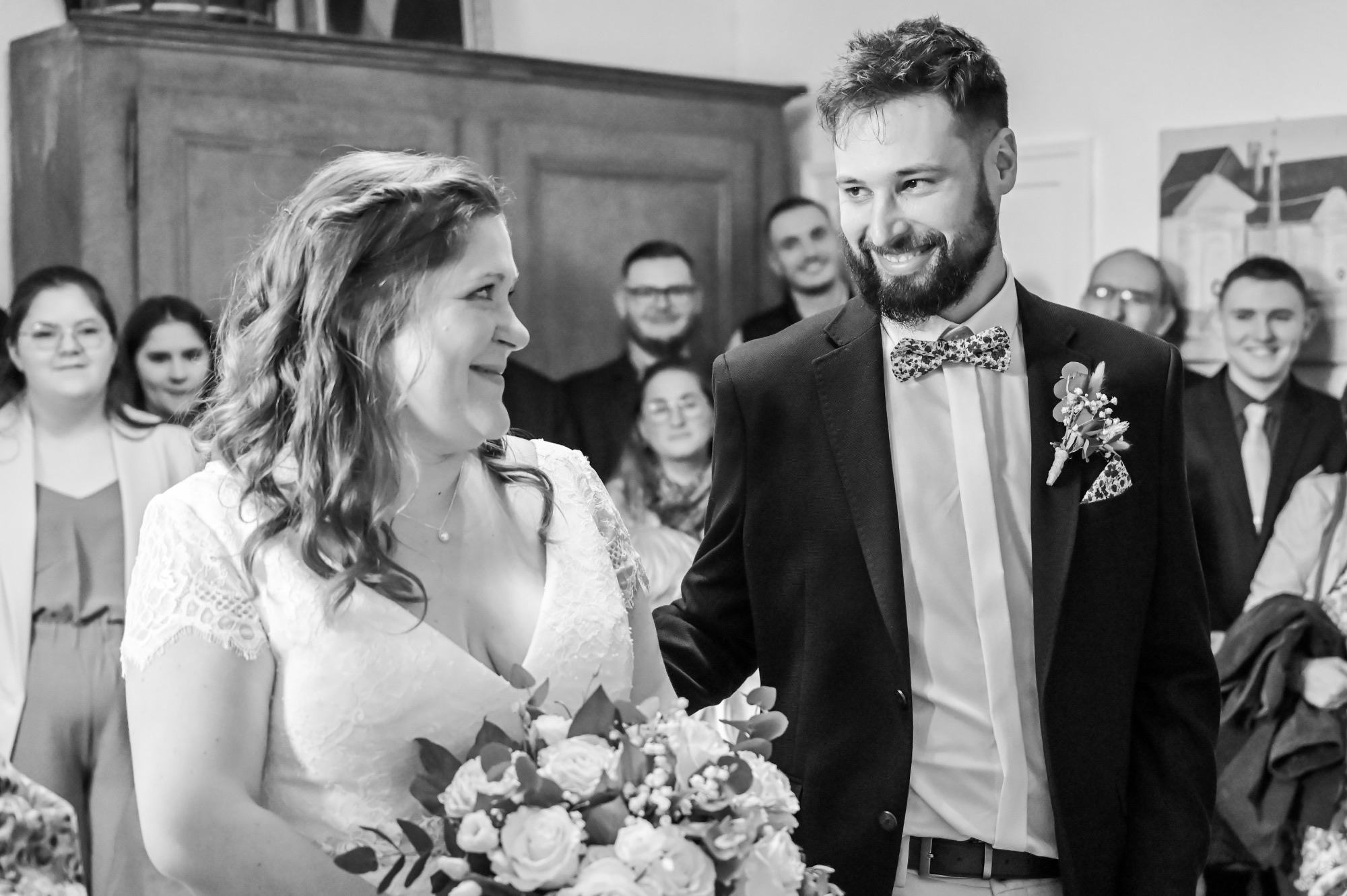 Couple heureux lors de leur mariage, entouré d'invités souriants.