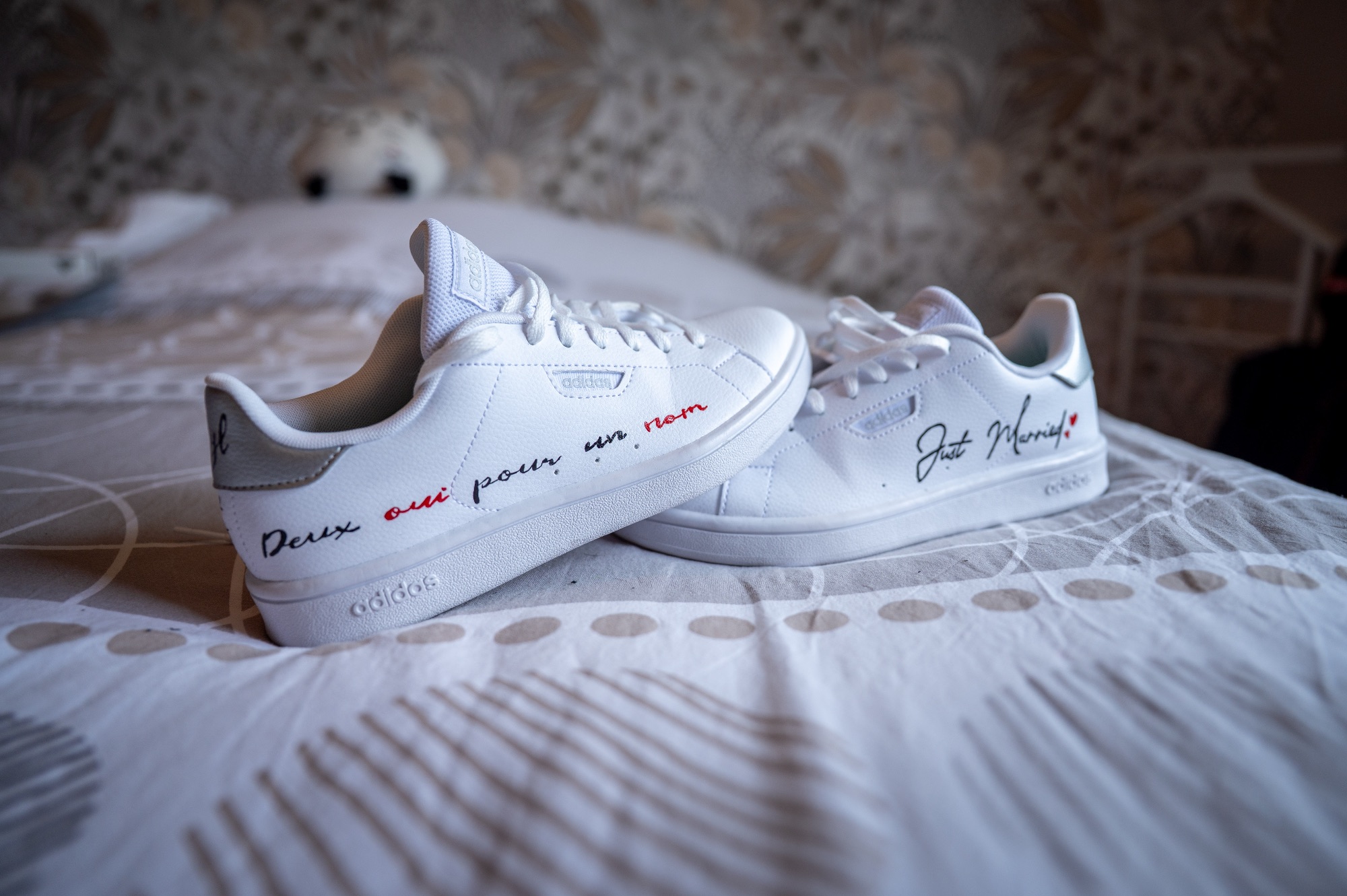 Baskets blanches avec inscriptions sur un lit