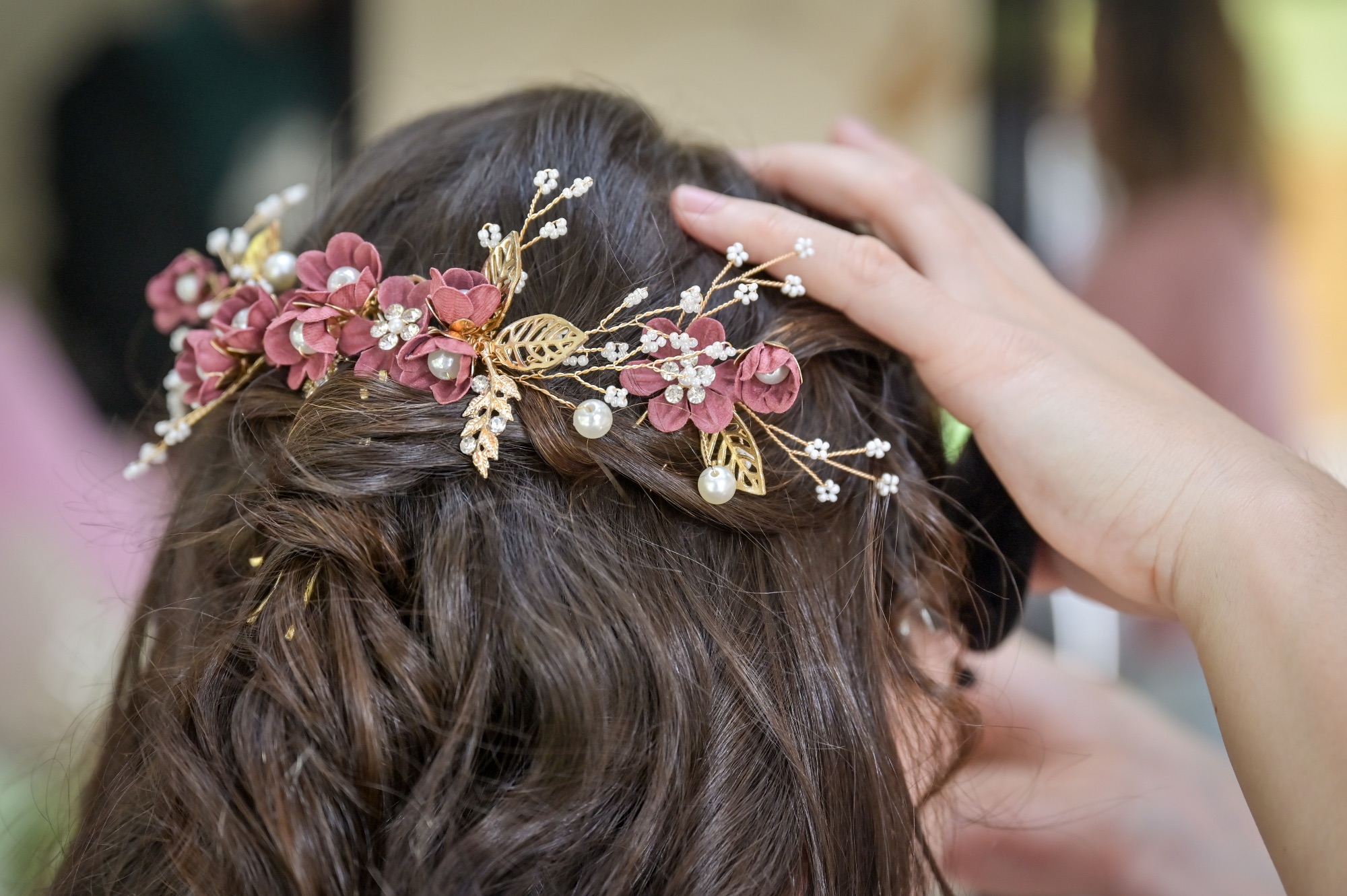 Coiffure de mariée ornée de fleurs et perles, prise de vue rapprochée.