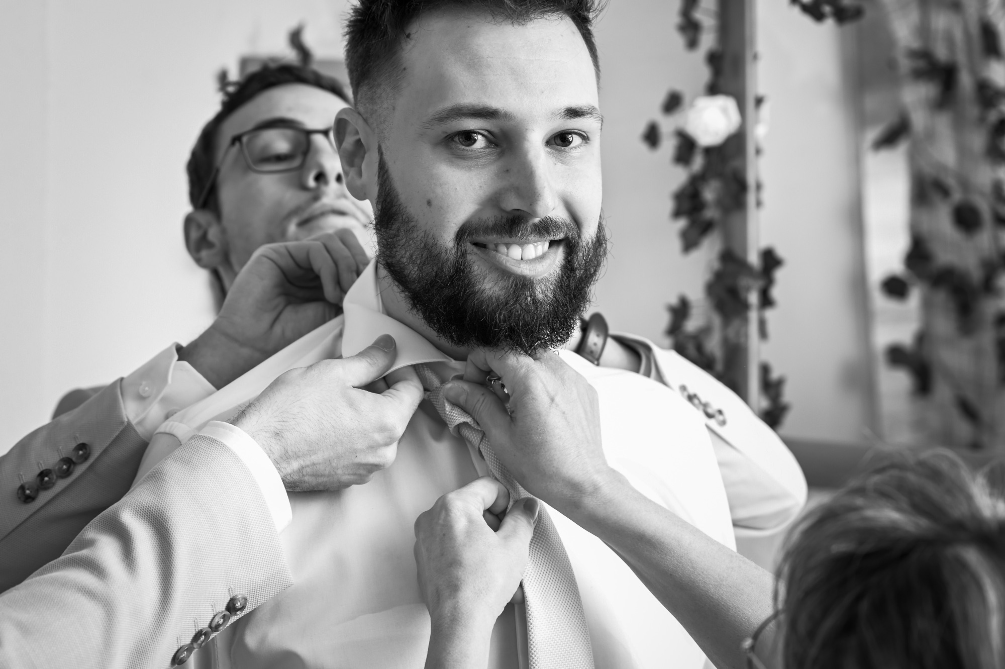 Homme souriant se préparant pour son mariage avec des amis.