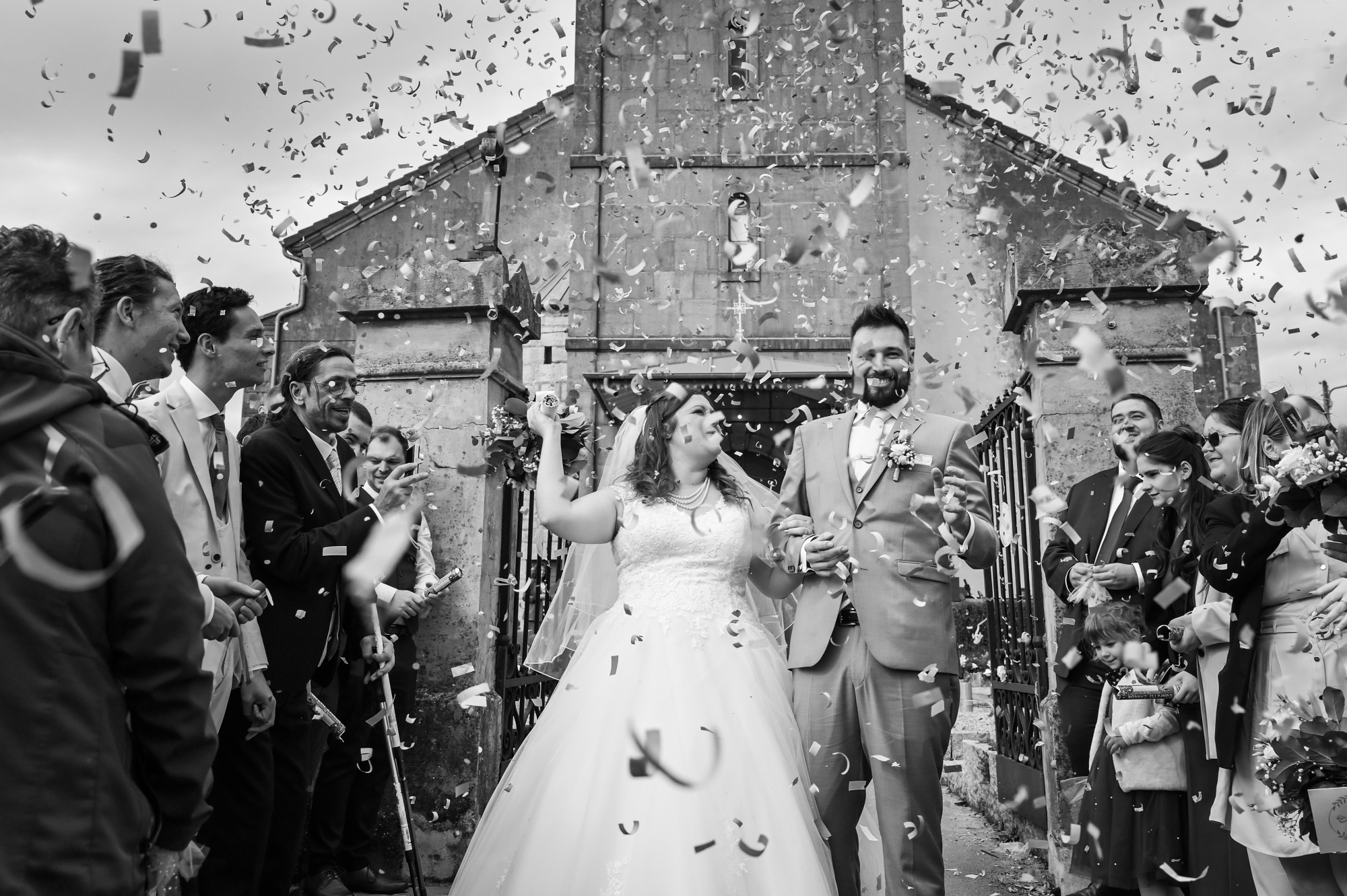 Couple de mariés célébrant leur union sous une pluie de confettis.