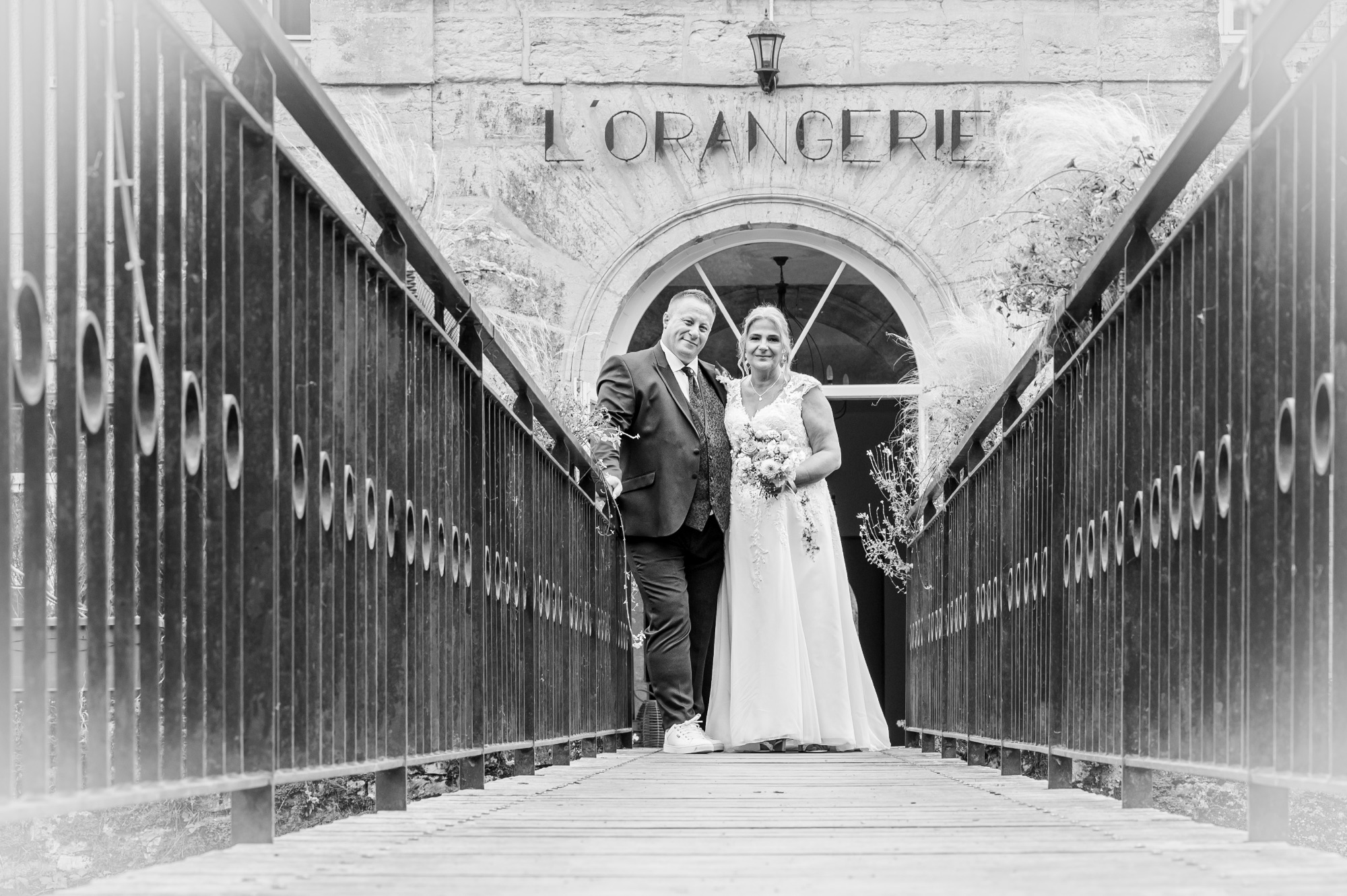 Couple de mariés posant sur un pont, ambiance romantique et naturelle.