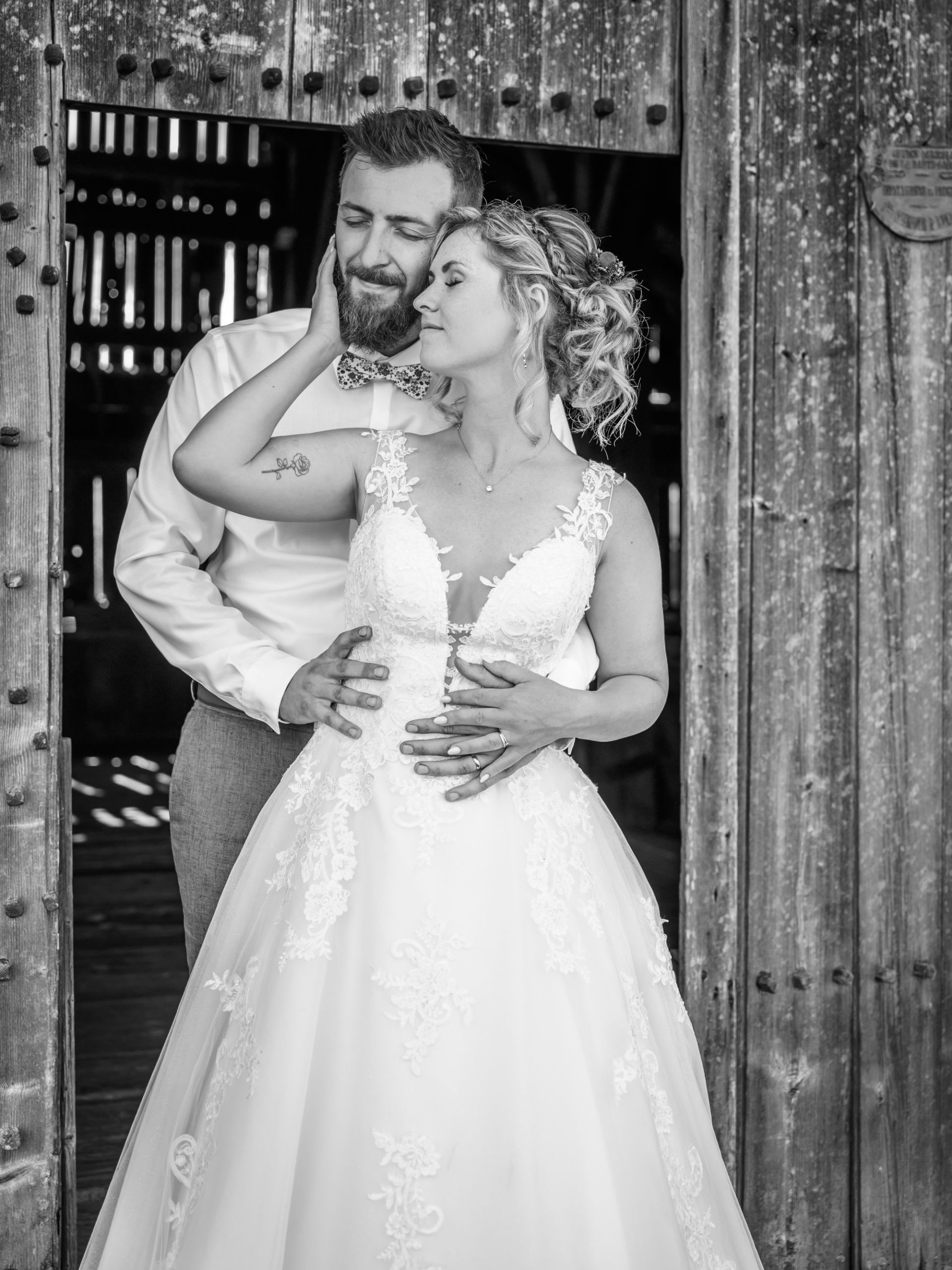 Couple de mariés posant dans une grange, moment romantique et authentique.