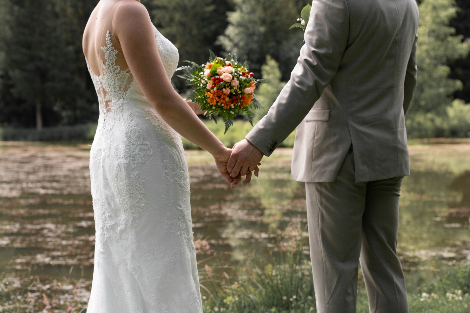 Mariage en plein air avec couple se tenant par la main et bouquet