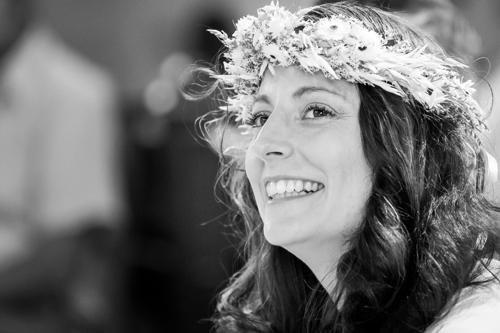 Femme souriante avec une couronne de fleurs lors d'un mariage.