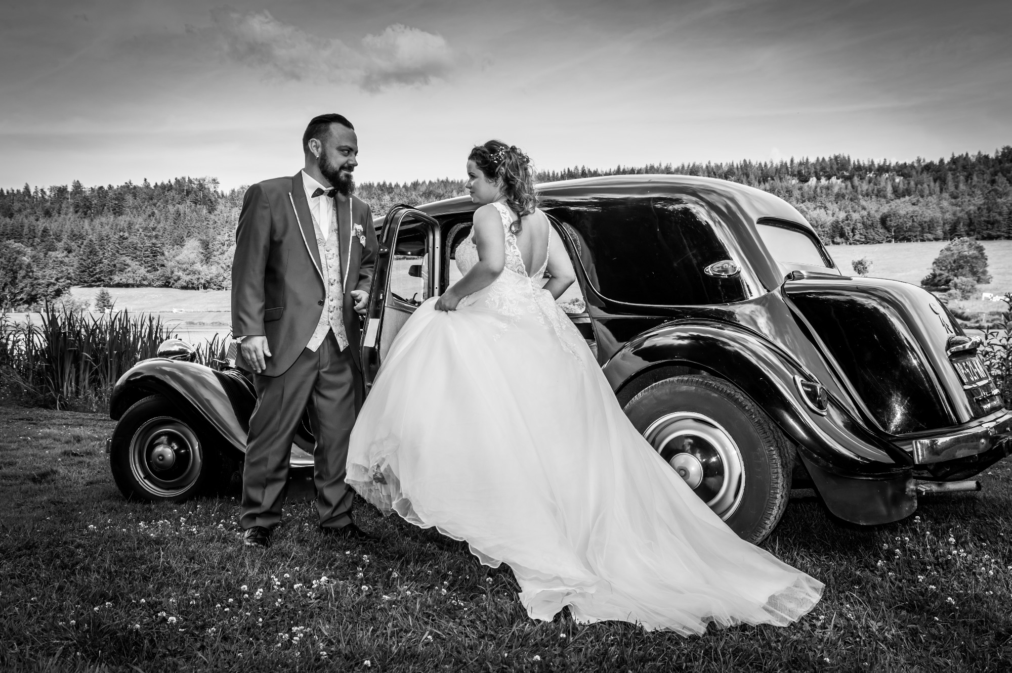 Mariage en extérieur avec couple devant une voiture classique.
