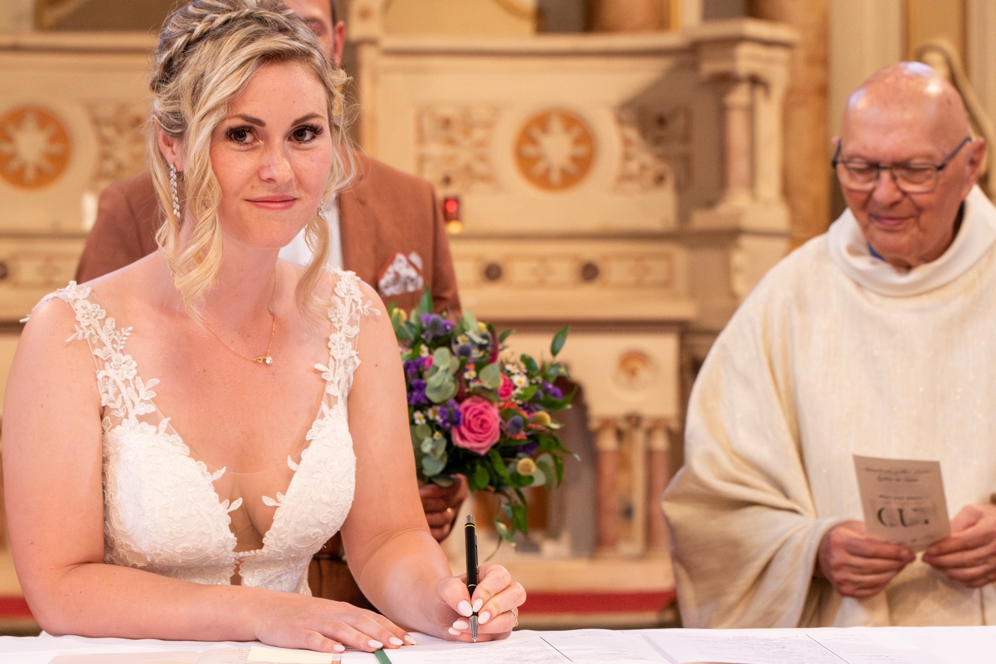 Mariée souriante signant son acte de mariage dans une église.