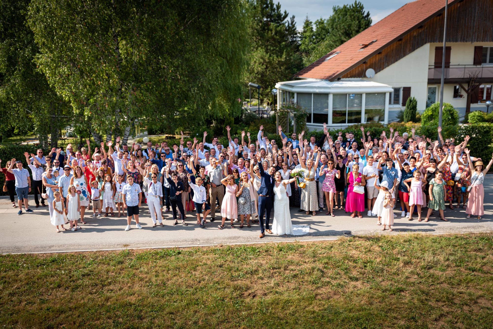 Photo de groupe de mariage avec les mariés et leurs invités en extérieur